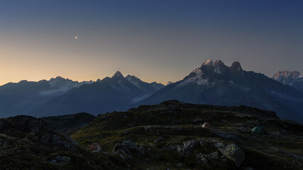 Fototapeta na wymiar Alps before sunrise with moon and three tents