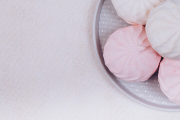 Tasty sweet zephyr on a plate and tablecloth background. Top view.
