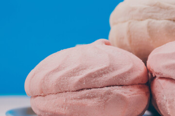 Tasty sweet zephyr on a plate and blue background.