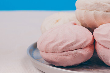 Tasty sweet zephyr on a plate and blue background.