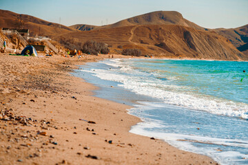  Sunny landscape of seaside shore with view of sandy beach, waves, cape Chameleon. Black Sea, Crimea