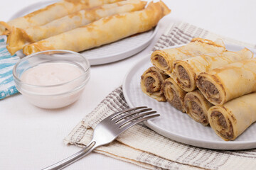 Meat stuffed crepes served with sauce. 