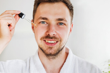 Close up of young smiling handsome man going to apply serum