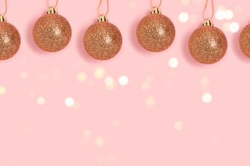 Golden glittering Christmas balls hanging on a pink background. Greeting card template.