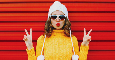 Winter portrait young woman blowing red lips sending sweet air kiss wearing yellow knitted sweater...