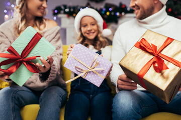 Obraz na płótnie Canvas Christmas presents in hands of joyful family on blurred background