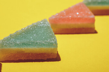 Colorful triangular jelly candy on yellow background. Macro shot.