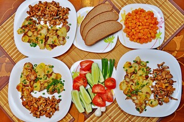 Fried potatoes with mushrooms beautifully chopped salad on a wooden table for a family of three, Top view