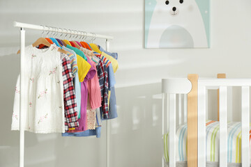 Different clothes hanging on rack in bedroom