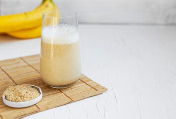 Healthy banana smoothie on wooden board with maca and protein on white background Copyspace