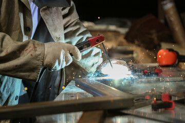 welder welds a metal structure in a workshop with electrical welding