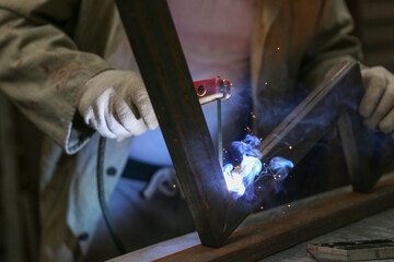welder welds a metal structure in a workshop with electrical welding