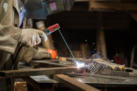 welder welds a metal structure in a workshop with electrical welding