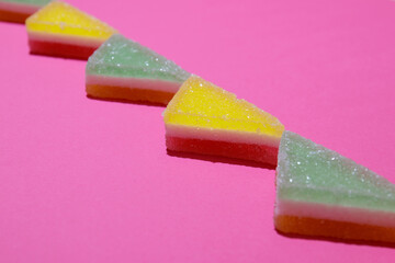 Colorful triangular jelly candy on pink background.