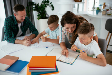 Parents helping the kids with their homework. Litlle boys learning at home