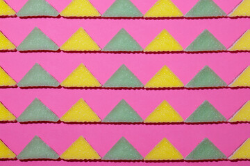 Lines of triangular jelly candy on pink background.
