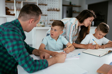 Obraz premium Parents helping the kids with their homework. Litlle boys learning at home