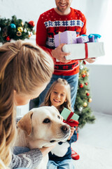 woman cuddling dog near daughter and husband with gifts on christmas