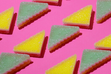 Lines of triangular jelly candy on pink background.