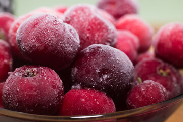 Ready acerola juice with frozen acerolas on the side. vibrant and natural colors. Rich in vitamin C, natural and healthy. rustic wooden table with black background.