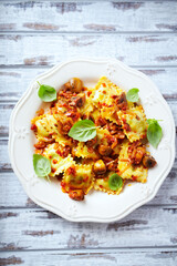 Ravioli with mushrooms and fresh basil. Bright wooden background. Top view. 