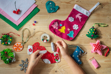 Christmas crafting, hands holding needle and sewing felt christmas sock for christmas and new year...
