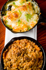 Steakhouse side dishes. Asparagus, salad, tomatoes, mashed potatoes, red onions, cream cauliflower, pickled peppers, seasoned meats served in cast iron skillet. Traditional appetizer items.