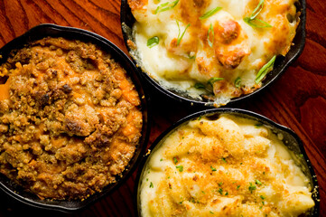 Steakhouse side dishes. Asparagus, salad, tomatoes, mashed potatoes, red onions, cream cauliflower, pickled peppers, seasoned meats served in cast iron skillet. Traditional appetizer items.