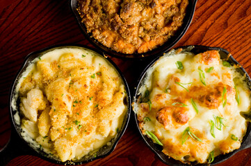 Steakhouse side dishes. Asparagus, salad, tomatoes, mashed potatoes, red onions, cream cauliflower, pickled peppers, seasoned meats served in cast iron skillet. Traditional appetizer items.