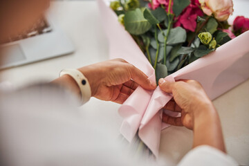 Fototapeta premium Certified florist wrapping a bouquet of flowers into decorative paper