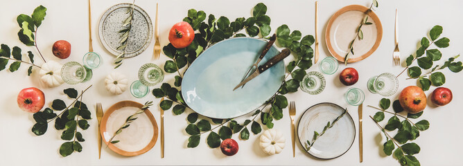 Autumn Thanksgiving, Friendsgiving, family gathering dinner table setting. Flat-lay of white Fall table with tableware and cutlery decorated with pumpkins, fruits and green leaves, top view - 387162043