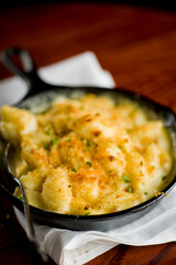 Steakhouse side dishes. Asparagus, salad, tomatoes, mashed potatoes, red onions, cream cauliflower, pickled peppers, seasoned meats served in cast iron skillet. Traditional appetizer items.