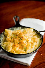 Steakhouse side dishes. Asparagus, salad, tomatoes, mashed potatoes, red onions, cream cauliflower, pickled peppers, seasoned meats served in cast iron skillet. Traditional appetizer items.