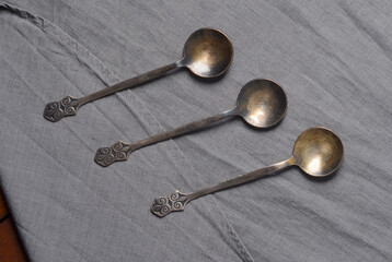 Ancient metal tablespoons on grey fabric close-up
