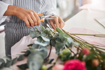 Experienced florist trimming flowers before making a bouquet
