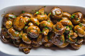 Fototapeta premium Mushrooms roasted in garlic, onions, olive oil and fresh herbs and spices. Classic American steakhouse or French bistro appetizer or side dish.