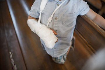 A kid with broken arm and cast on it. Young boy in pain standing.