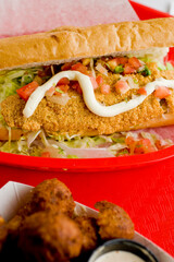Fried fish or po boy sandwich. Classic Cajun cuisine: fried fish sandwich served on toasted bun w/onions, lettuce, tomato, mayo, salt & pepper. Classic New Orleans sandwich favorite.