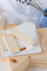 Slices of traditional farm cheese with white mold on a wooden stand in the shape of a star