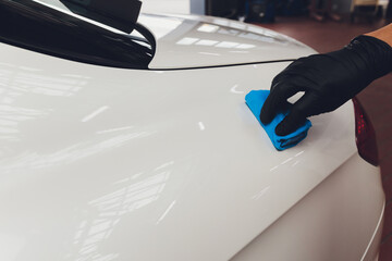 Car detailing - Man applies nano protective coating to the car. Selective focus.