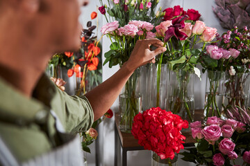 Florist picking one flower from a glass container