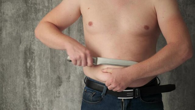The concept of getting rid of excess weight.fat man cuts off fat deposits with belly knife