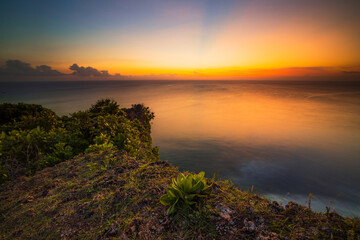 Fototapeta na wymiar Seascape. Spectacular view from Uluwatu cliff in Bali. Sunset time. Blue hour. Ocean view. Colorful sky. Nature concept. Soft focus. Slow shutter speed.
