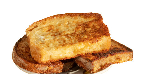 Egg-fried croutons of white and black bread. In the background is a yellow cup with milk. Illuminated by bright daylight. Isolated on white background.