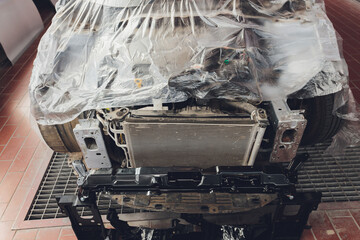 A broken car color silver, wrapped in a plastic coating. The car is covered with polyethylene after...
