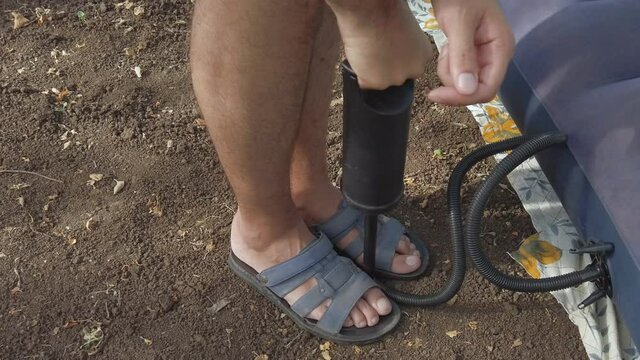 A man inflates an air mattress with an air hand pump