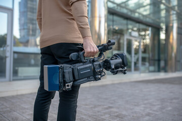Cameraman holding camera in his right hand outside