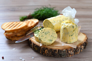 Healthy butter with dill, parsley in the form of a roll, slices for easy use. Herbal butter on a cutting board for toasted, sandwiches
