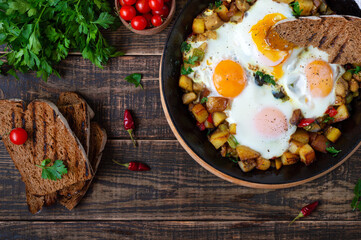 Fototapeta na wymiar Fried eggs with vegetables - shakshuka in a frying pan and rye bread on an old wooden background. Late breakfast. Rustic style. Middle eastern traditional dish. Flat lay. Top view