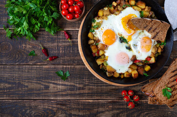 Fried eggs with vegetables  - shakshuka in a frying pan and rye bread on an old wooden background. Late breakfast. Rustic style. Middle eastern traditional dish.  Flat lay. Top view